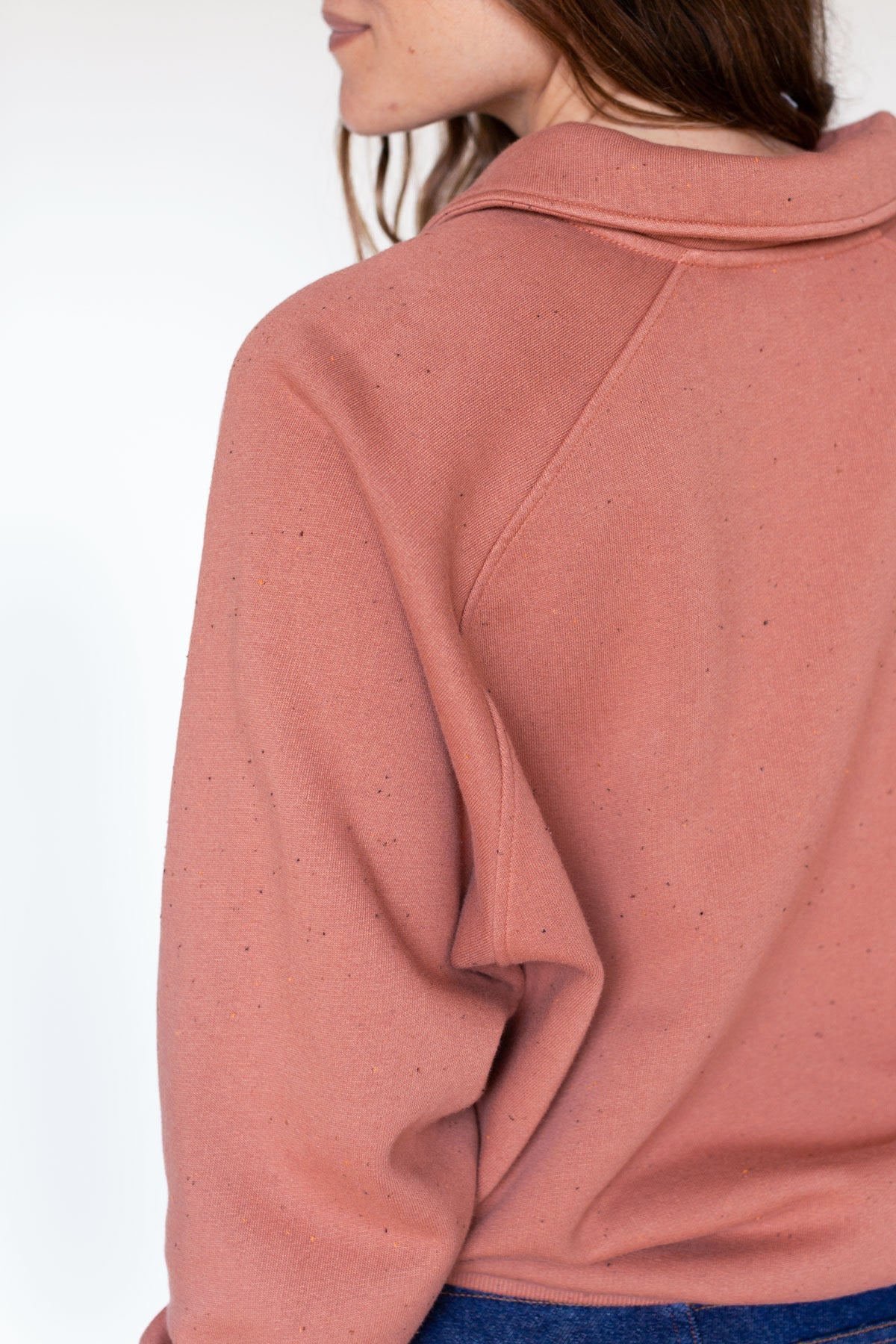 Back view detail showing the raglan sleeve seam of an adobe rose polo sweatshirt.