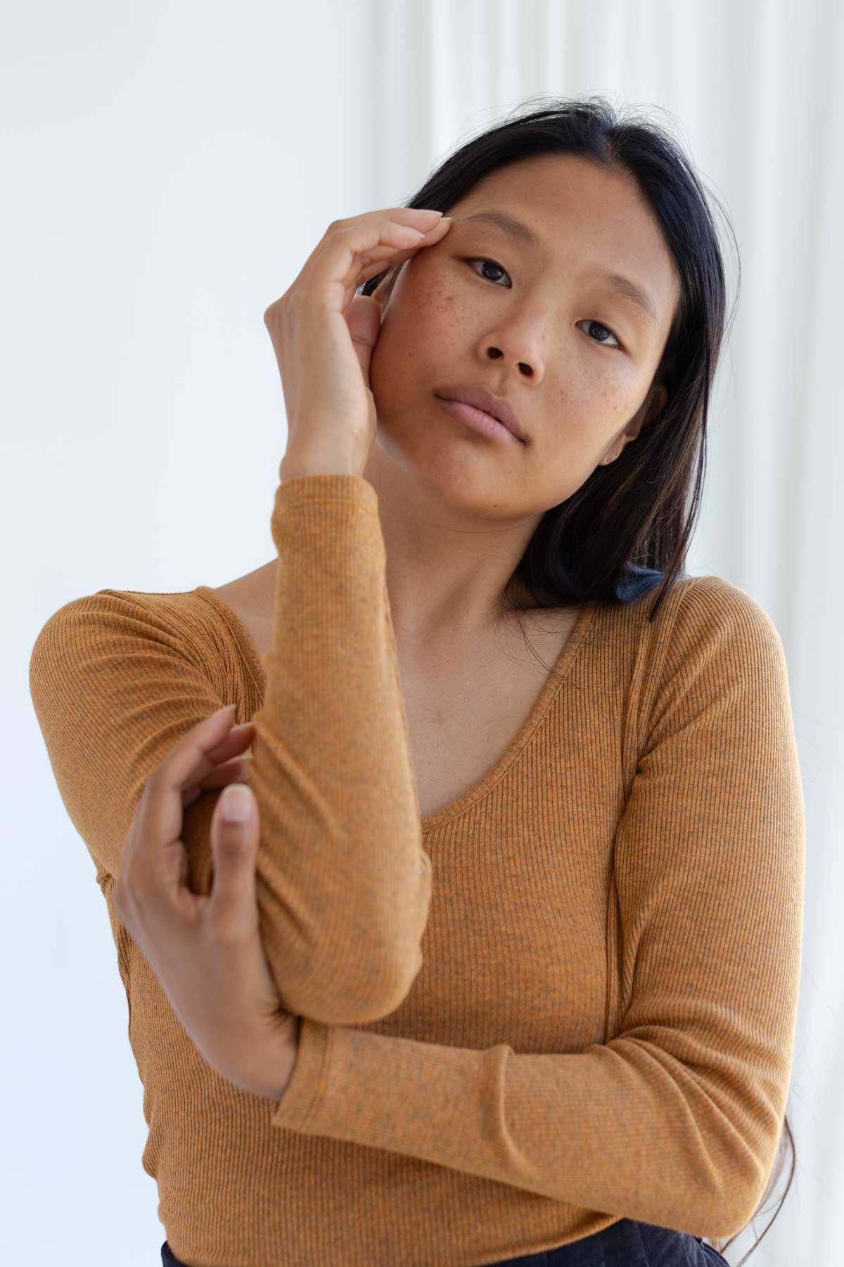 Woman wearing a nugget-yellow ribbed long sleeve top.