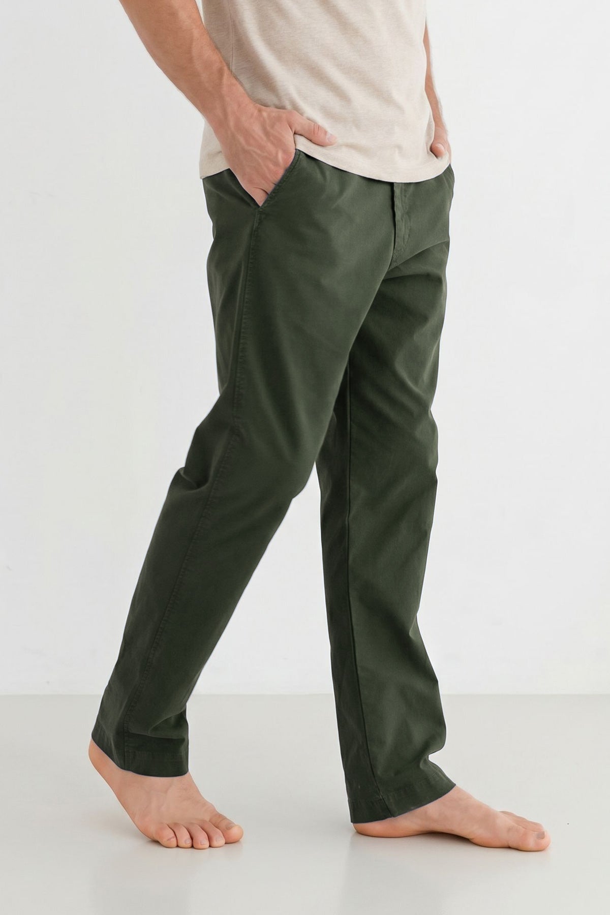 Cropped side view of a man wearing dark moss green straight-leg pants.