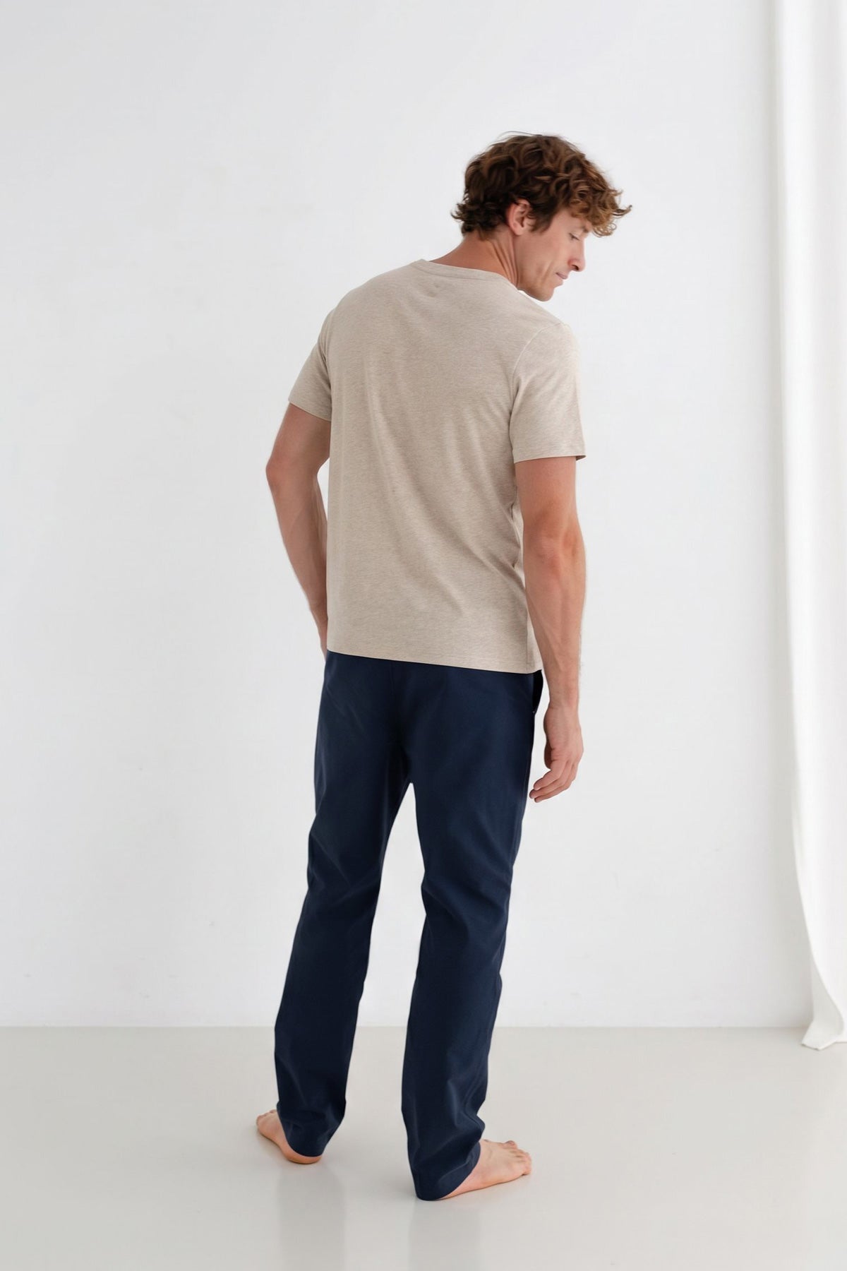 Back view of man wearing a beige t-shirt and midnight blue pants.