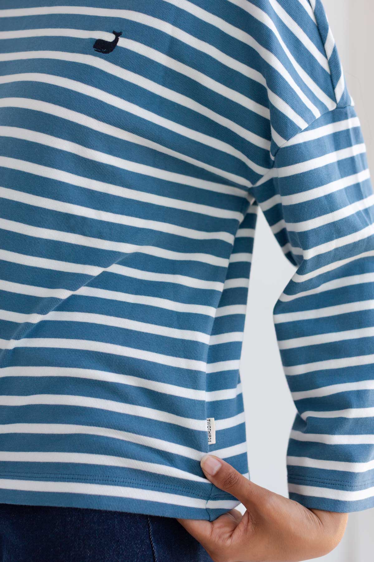 Close-up of a dusty blue and white striped shirt with a small embroidered whale.