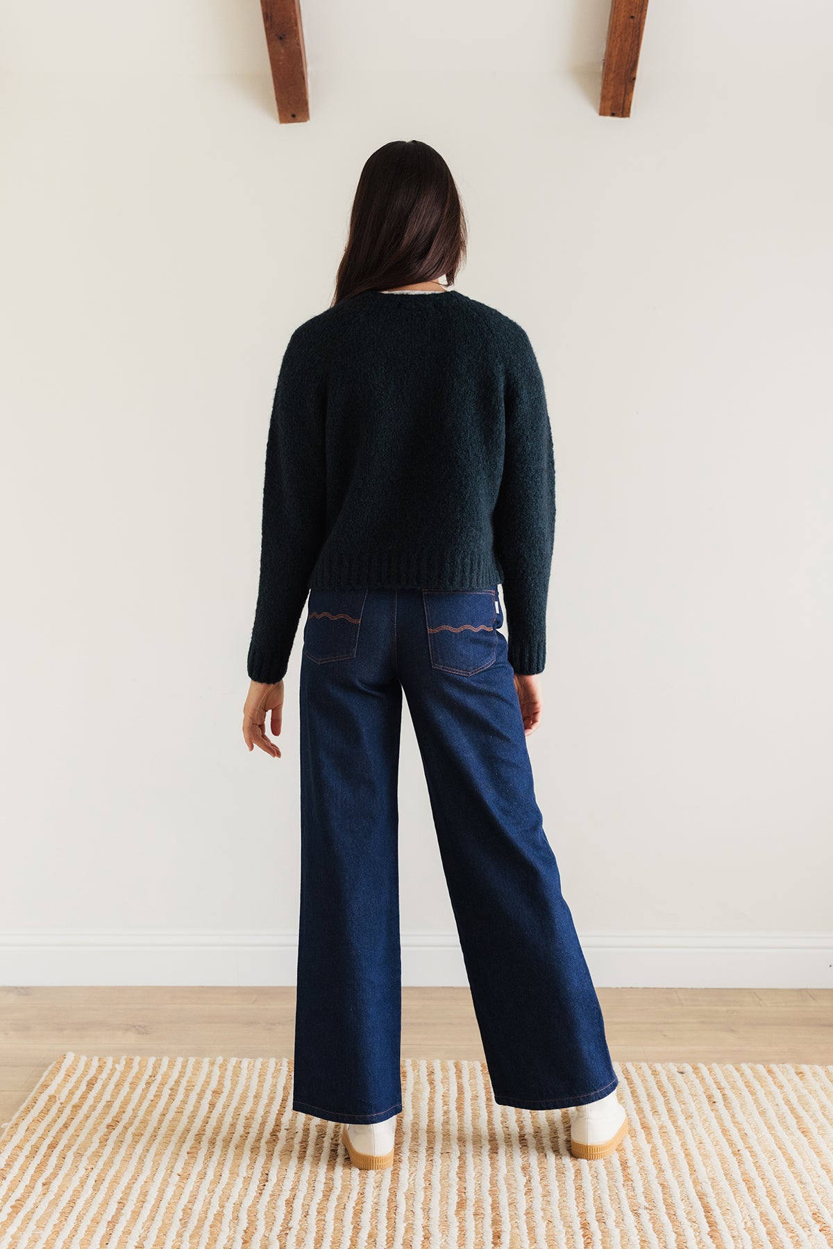 Back of women`s dark green sweater and blue jeans 